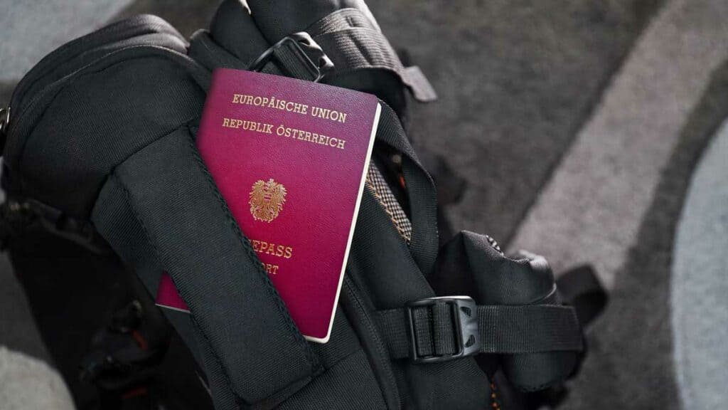 בתמונה נראה דרכון אוסטרי אדום מונח על תרמיל שחור.