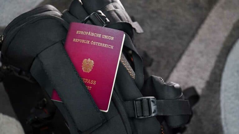 בתמונה נראה דרכון אוסטרי אדום מונח על תרמיל שחור.